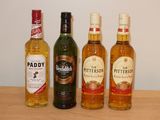Trois bouteilles d'alcool sont alignées sur une table en bois