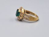 an image of a gold ring with a green stone surrounded by white diamonds