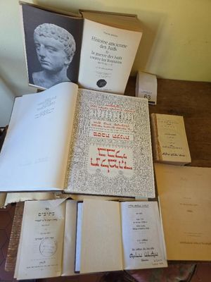 several books on a table with a statue of a head on top of it
