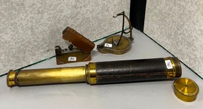 un télescope doré posé sur une étagère en verre, à côté d'un briquet