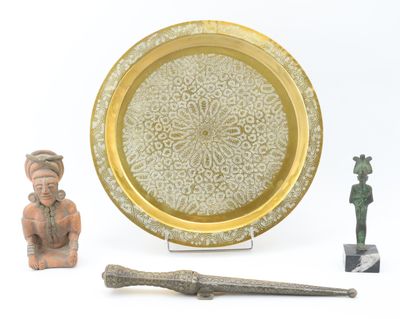 une assiette en or décorée d'un motif, à côté d'un couteau et d'une figurine