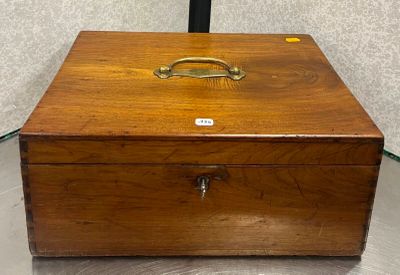 une petite boîte en bois munie d'une poignée, posée sur une table en verre