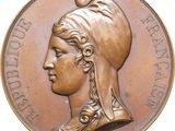 an old bronze medal with a woman ' s head and a feather on it