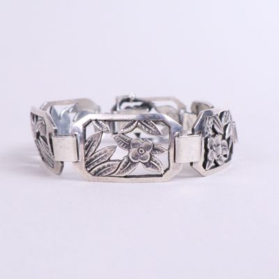 un gros plan d'un bracelet en argent orné de fleurs
