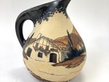a small vase with a picture of a house on it