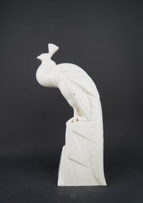 a white sculpture of a peacock sitting on top of a rock