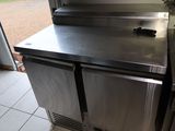 un plan de travail en inox avec un réfrigérateur en arrière-plan