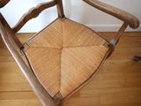 a wooden chair with a wicker seat on a hard wood floor