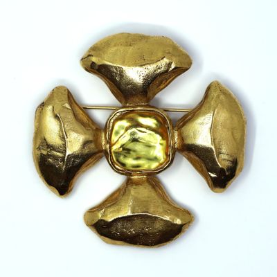 yellow stone cross broochle on white surface with white background