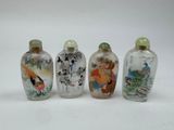 four glass snuff bottles with asian designs on them