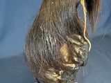 someone is holding a doll with a long hair on it ' s head