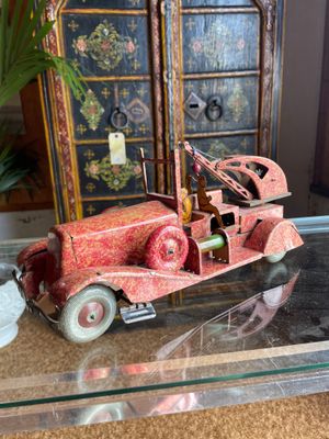 a red toy car sitting on a glass table next to a vase