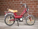 a small red motorcycle parked in front of a brick wall