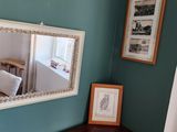 a picture of a corner of a room with a mirror on the wall and pictures on the wall