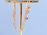 un collier plaqué or posé sur un socle avec un fond bleu