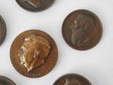 six bronze coins with portraits of men on them on a white surface