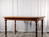 La table est en bois et possède des pieds tournés.