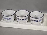 three white cups with blue rims are on a tray with a spoon
