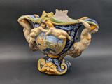 a blue and yellow vase with a statue on it