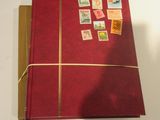 un livre rouge orné de timbres, posé sur une table