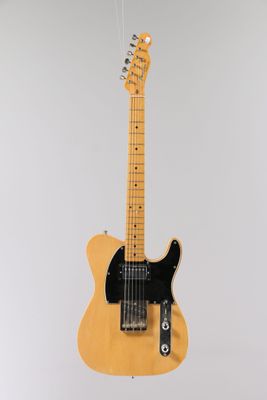 an electric guitar hanging from a string on a wall