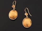 a pair of gold earrings with a yellow stone in the center