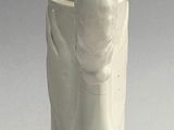 a white vase with a banana in it sitting on a table