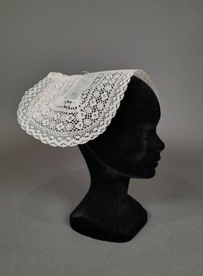 un gros plan sur la tête d'un mannequin coiffée d'un chapeau en dentelle blanche