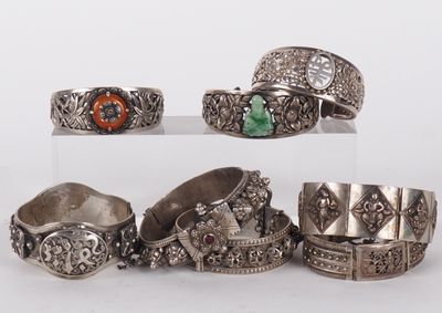 plusieurs types de bagues et de bracelets en argent disposés sur un fond blanc