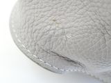 someone ' s hand is holding a white leather purse on a white surface