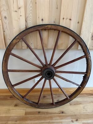 une grande roue en bois posée par terre près d'un mur