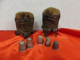deux dés à coudre anciens et une paire de dés à coudre posés sur un tissu rouge