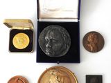 an assortment of gold and silver medals including a bust of a woman