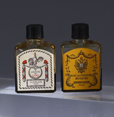 two bottles of cologne sitting on a shelf next to each other