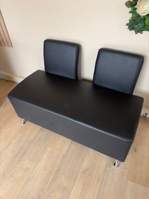 un banc en cuir noir sur lequel sont posées deux chaises noires