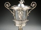 an antique silver plated cup on a stand with a bird on top