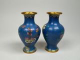 pair of blue vases with flowers on them sitting on a white surface