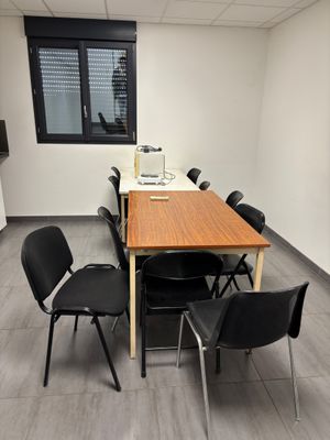 une longue table avec des chaises et un ordinateur portable posé dessus, dans une pièce