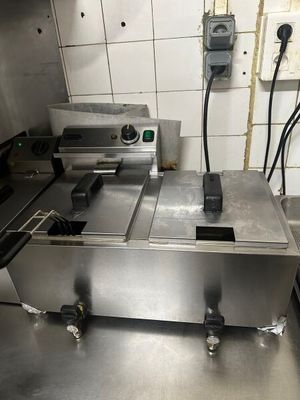 plan de travail en acier inoxydable équipé de deux friteuses et d'un four de comptoir