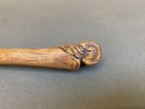 an old wooden stick with a carved handle on a table