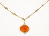 a gold necklace with an orange stone pendant on a gold chain