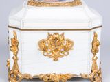 a white and gold box with a gold decoration on the lid