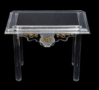 une table en plexiglas transparent avec un plateau noir et doré