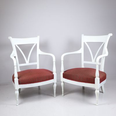 une paire de fauteuils peints en blanc avec des coussins rembourrés rouges