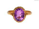 gros plan d'une bague en or avec une pierre violette