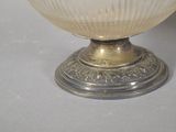 a white glass bowl with a silver base on a table