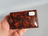 a hand holding a small tortoise shell case
