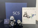 trois ours en argent posés sur une table, à côté d'un livre