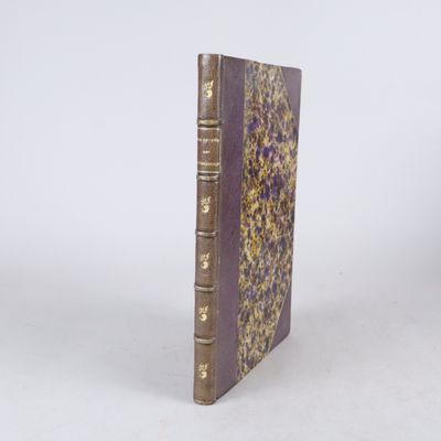 un vieux livre à la couverture violette posé sur une surface blanche