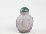 a small glass bottle with a green lid on a white surface
